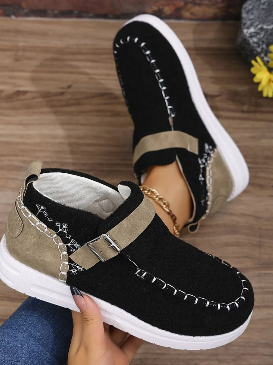 Black textured stitch-detail buckle sneakers with embroidered accents and tan trim.