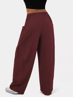 Burgundy maternity pants with wide legs and side pockets, styled with a black top and white sneakers.