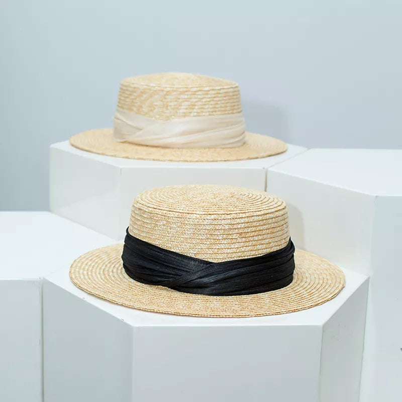 Straw boater hat with black ribbon trim, classic flat top and brim.