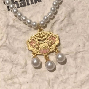 Gold lotus pendant necklace with pearl accents and a pearl strand.