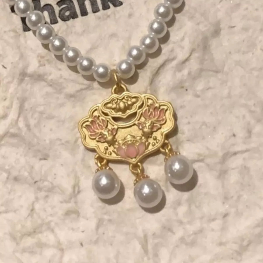 Gold lotus pendant necklace with pearl accents and a pearl strand.