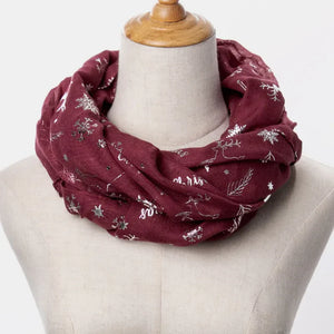 Burgundy infinity scarf with metallic Christmas print featuring snowflakes and reindeer.