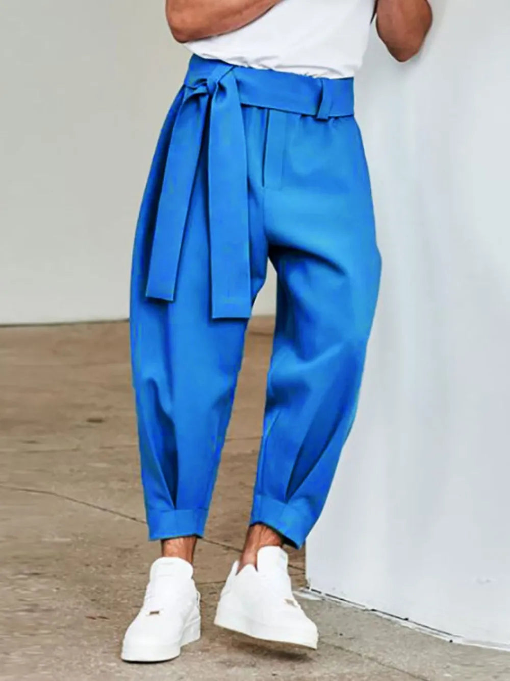 Blue balloon-leg wrap trousers with a tie waist, cuffed hem, and white sneakers.