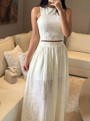 White eyelet crop top and maxi skirt set with pearl trim and intricate floral cutouts.