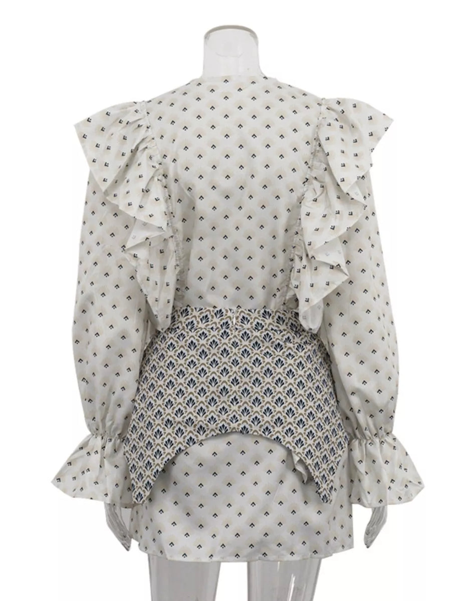 White patterned blouse with ruffled shoulders and cuffs, paired with a patterned peplum skirt.