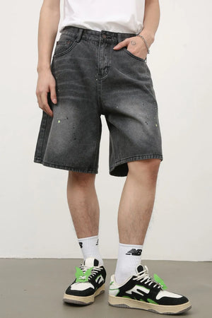 Dark wash denim bermuda shorts with artistic paint splatters and a relaxed fit.