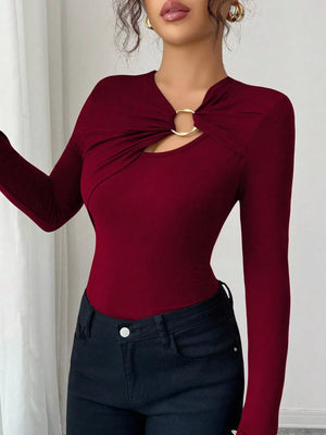 Burgundy long-sleeve tee with asymmetrical cutout and gold ring detail.
