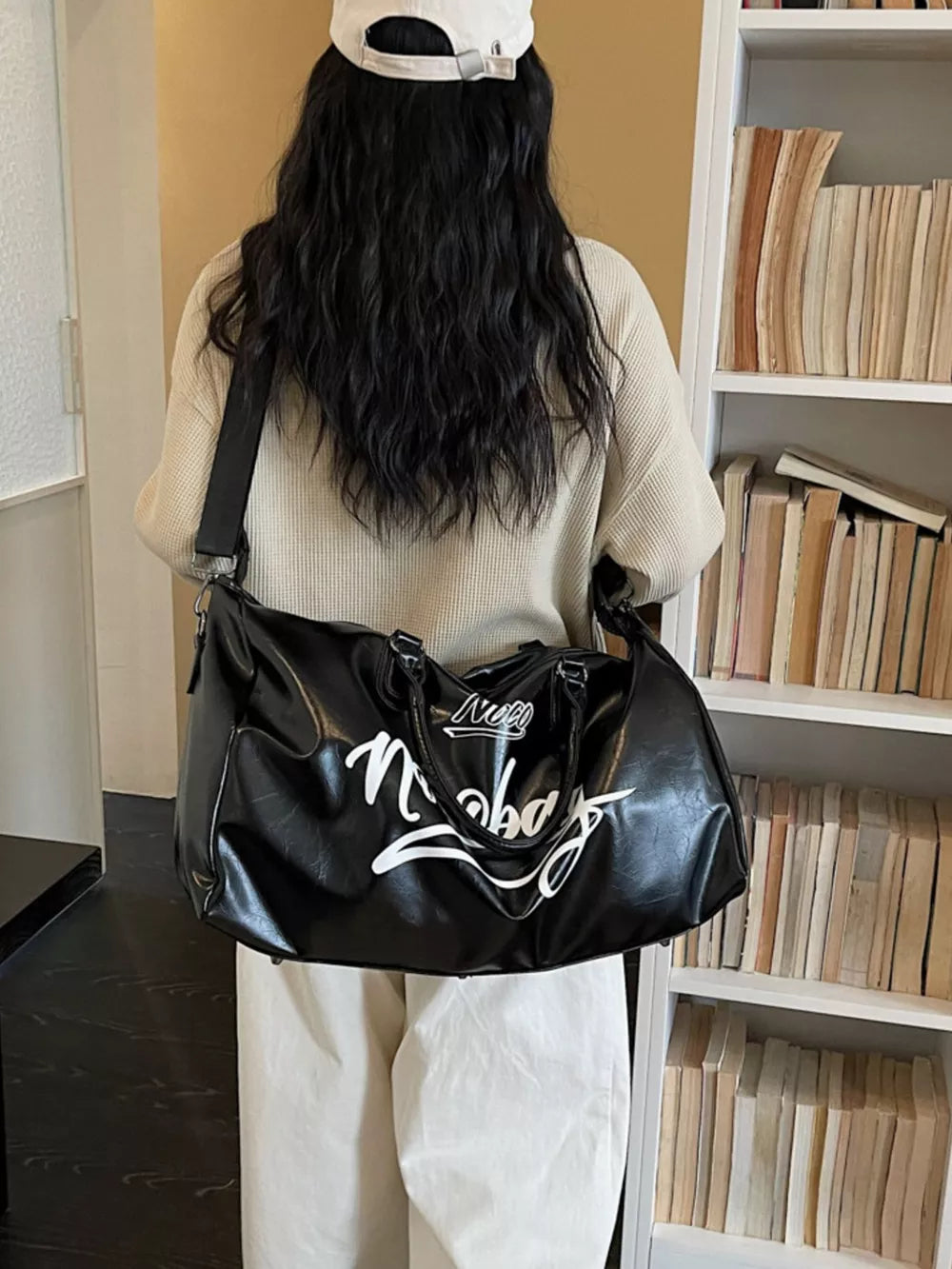 Sleek black PU leather travel bag with white script graphic, dual handles, and shoulder strap.
