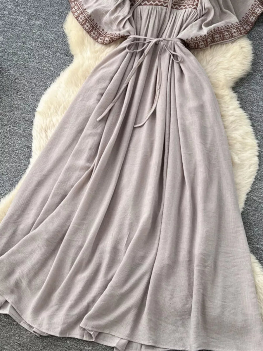 Grey V-neck maxi dress with embroidered details and tie waist.