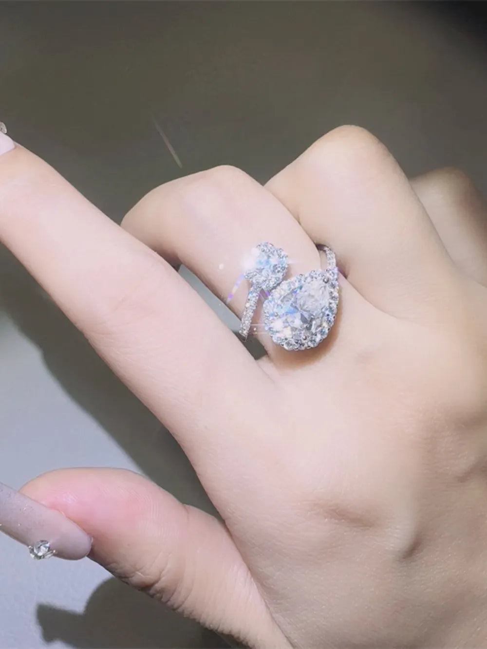 Silver halo engagement ring with bypass band and brilliant cut center stone.