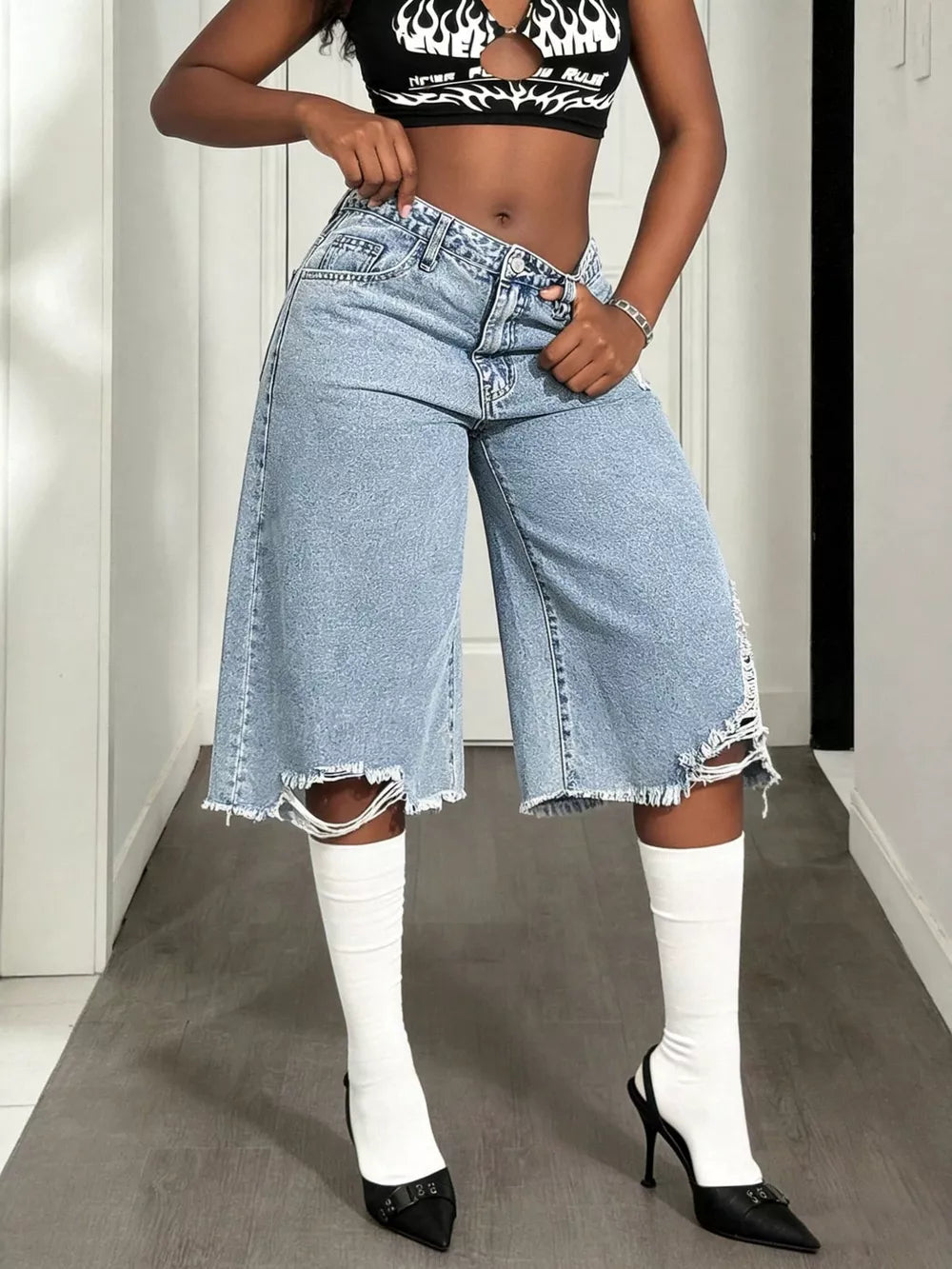 Distressed light wash denim wide-leg shorts with raw hem and thigh rips.