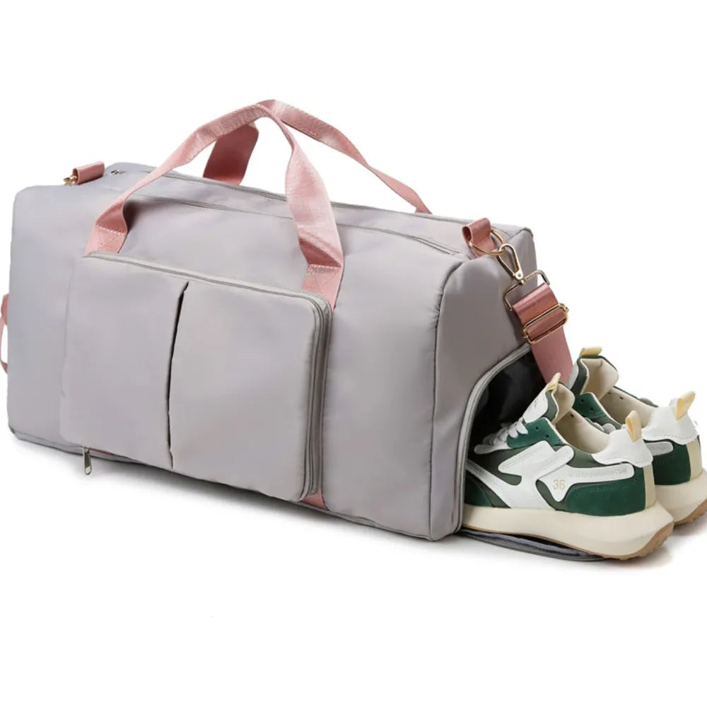 Light gray duffel bag with pink handles and shoe compartment, perfect for gym or travel.