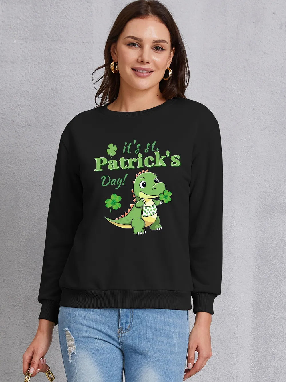 Black St. Patrick's Day sweatshirt with a cartoon dinosaur holding shamrocks and text.