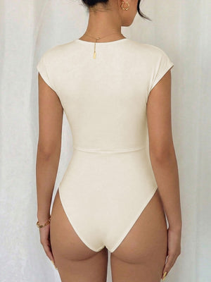 Cream cap sleeve bodysuit with surplice neckline and high-cut leg.