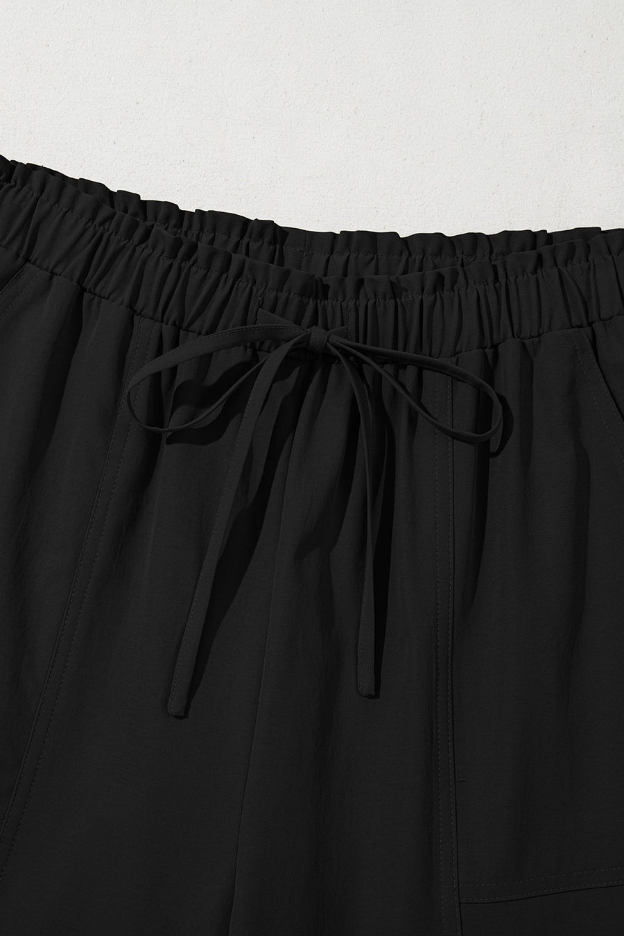 Black cropped drawstring pants with elastic waist and tie detail.