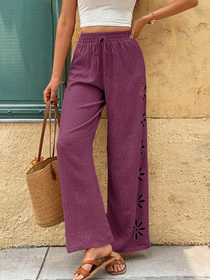Purple wide-leg pants with drawstring waist and floral cutouts on the side.