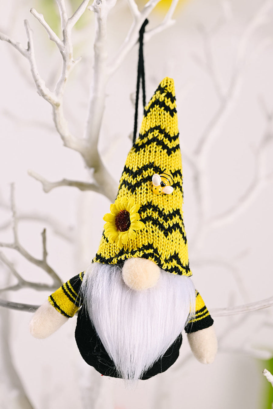 Yellow bee gnome ornament with sunflower and bee detail, hanging on a branch.