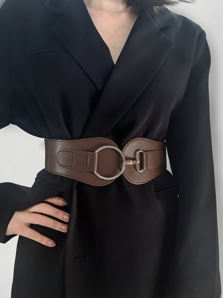 Brown elastic cincher belt with silver buckle detail worn over a black blazer.