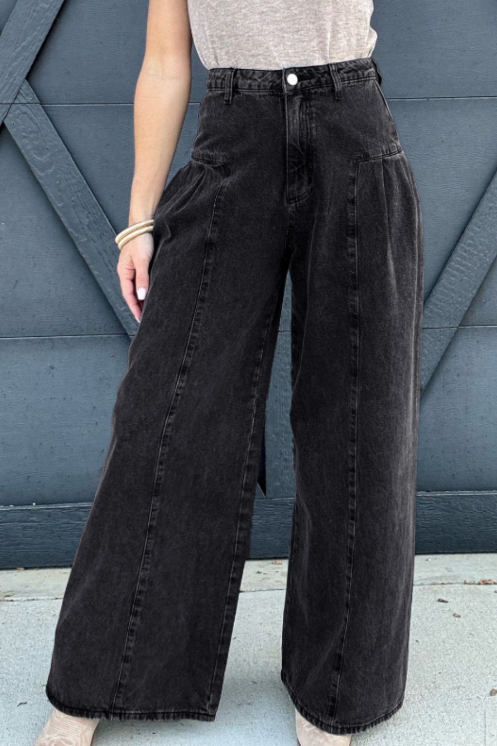 Black pleated front palazzo jeans with a wide leg and a washed denim finish.