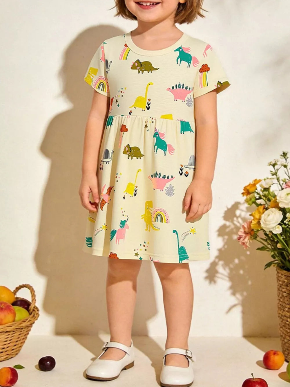 Toddler yellow cotton short sleeve dinosaur print dress with rainbow accents.