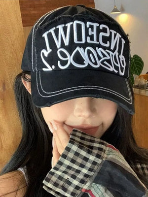 Black distressed baseball cap with white embroidered text and contrast stitching