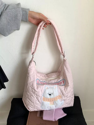 Blush pink quilted crossbody bag with a white bear applique wearing a scarf and "Lucky Puppy" text.