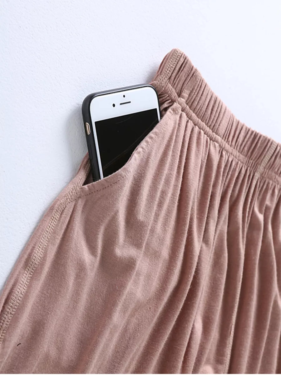 Pajama pants in Milk Tea Camel with elastic waistband and side pocket holding a smartphone.