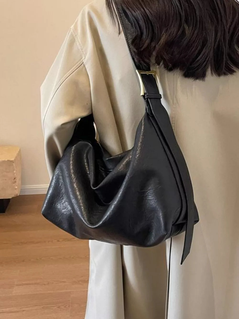 Black leather shoulder bag with adjustable strap and gold buckle detail