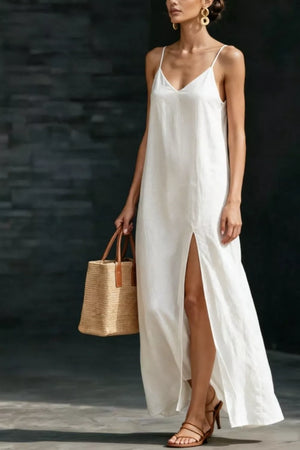 White V-neck maxi dress with spaghetti straps and a high slit, styled with a straw tote bag.
