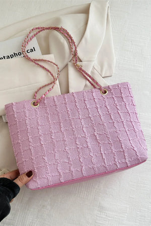 Pink bouclé shoulder bag with textured grid pattern and chain strap.