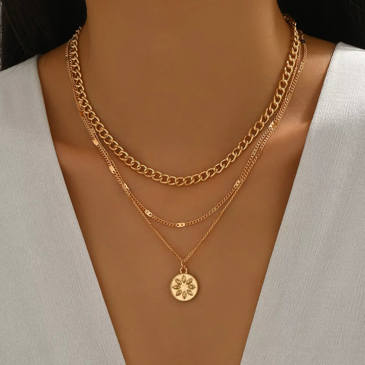 Gold layered pendant necklace with a floral coin charm and curb chain.