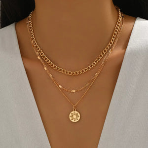 Gold layered pendant necklace with a floral coin charm and curb chain.