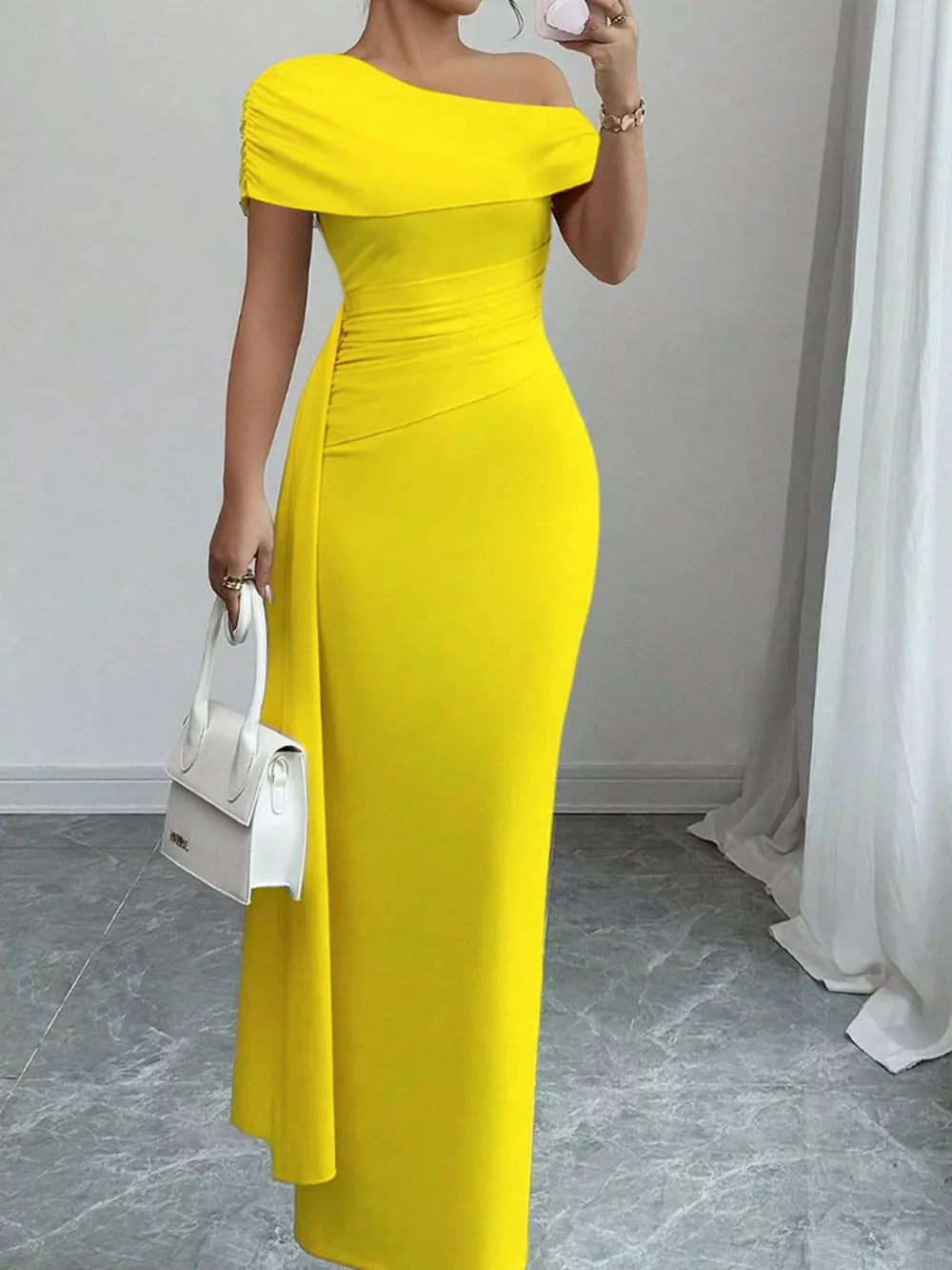 Yellow asymmetrical ruched maxi dress with off-the-shoulder neckline and body-hugging fit.