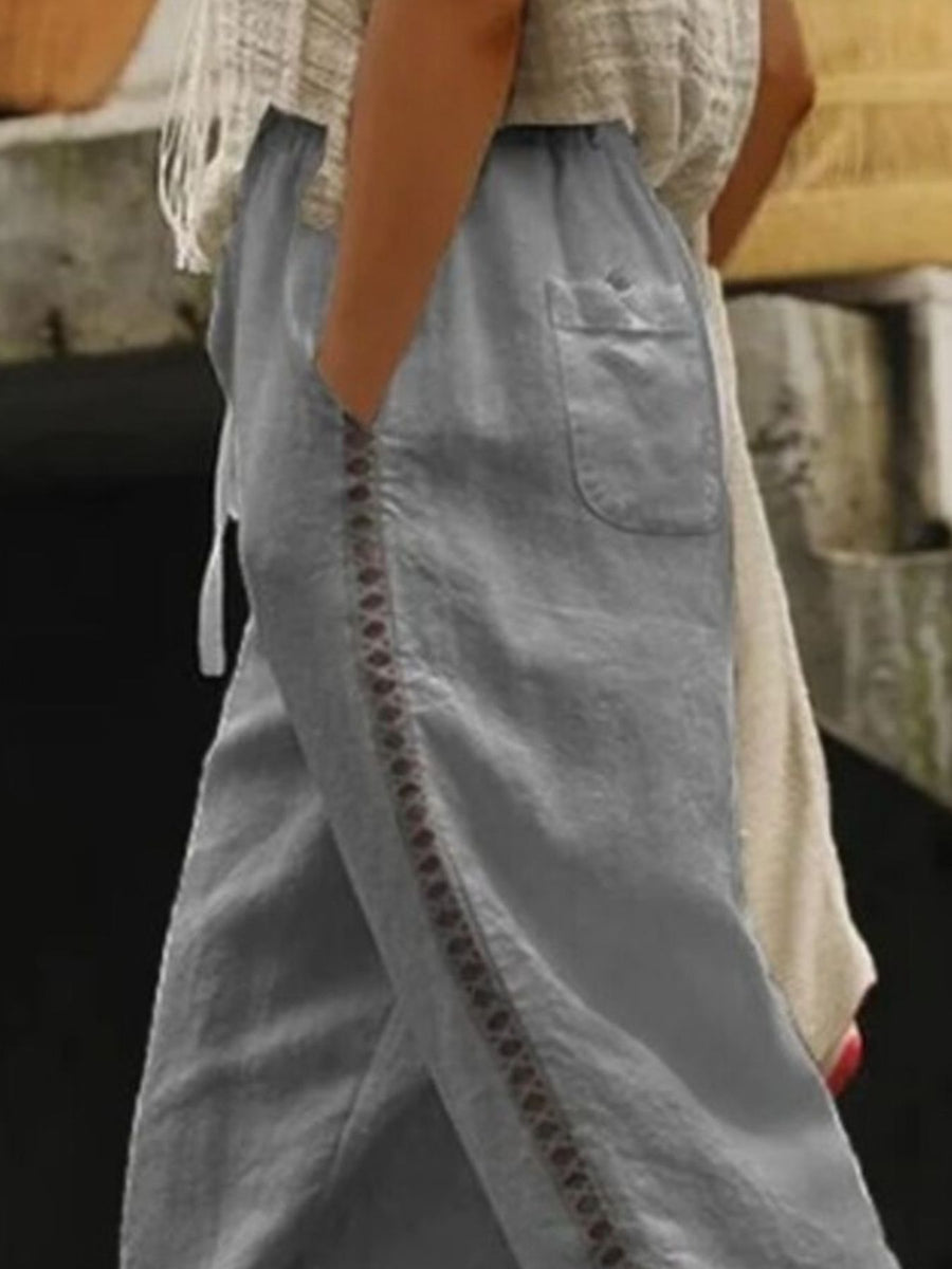 Grey relaxed cropped pants with hollow out trim detail and pockets.