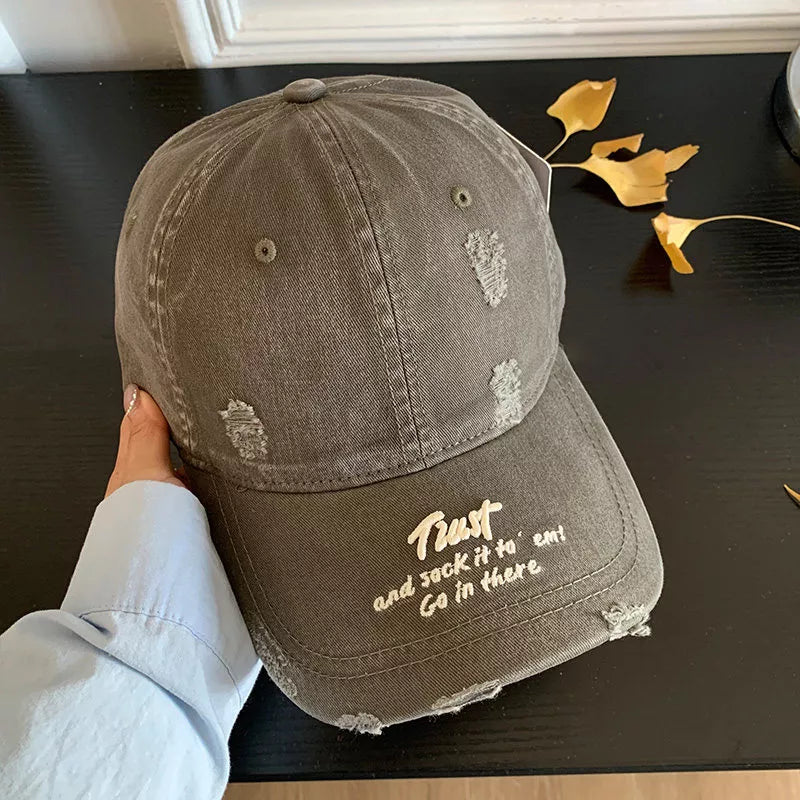 Distressed grey baseball cap with embroidered text and frayed details