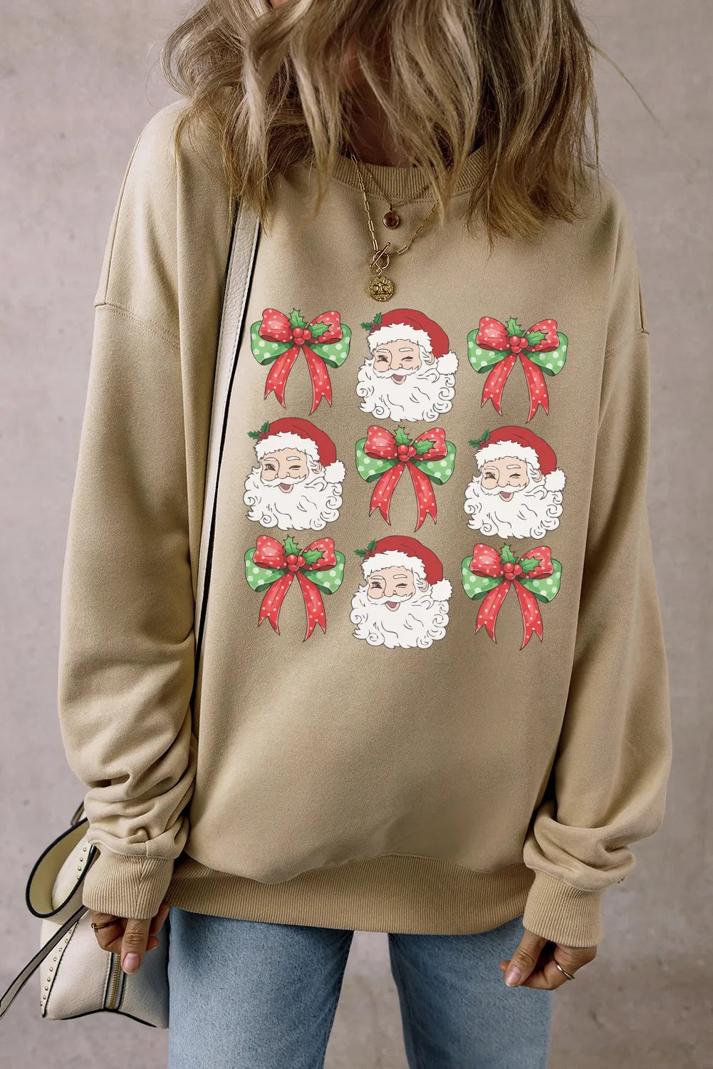 Khaki cotton crewneck sweatshirt with a grid of Santa faces and festive bows graphic.