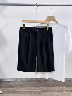 Black pleated chino shorts with pockets and button closure, styled with a white t-shirt.