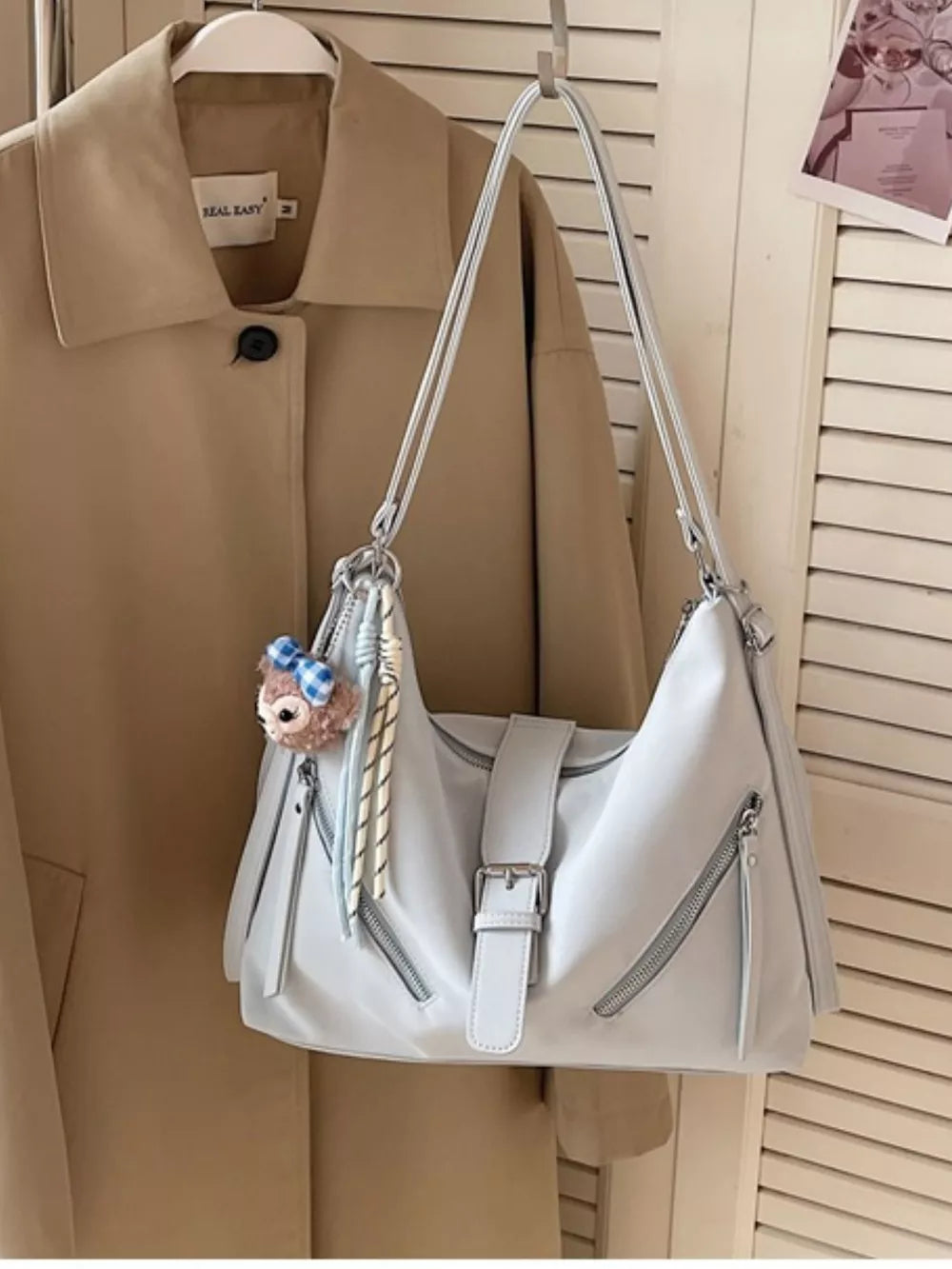 Light blue distressed leather shoulder bag with buckle and diagonal zippers, and a charm.