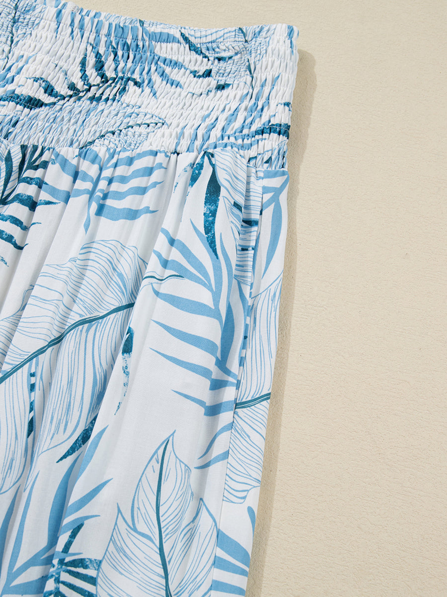 Tropical leaf print wide leg pants in white and blue with smocked waist and pockets.
