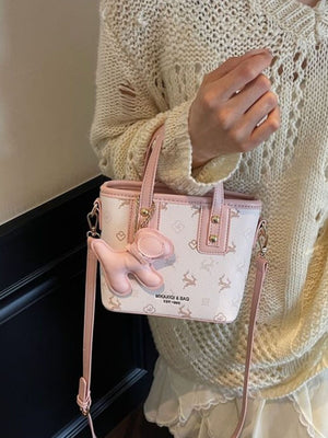 Charming mini crossbody bag in blush pink with a deer print and a cute pink charm.