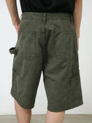 Utility denim carpenter shorts in washed olive with multiple pockets and a tool loop.