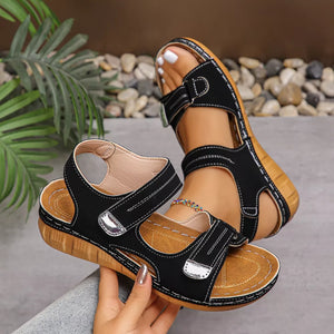 Black wedge sandals with adjustable straps and white stitching detail.