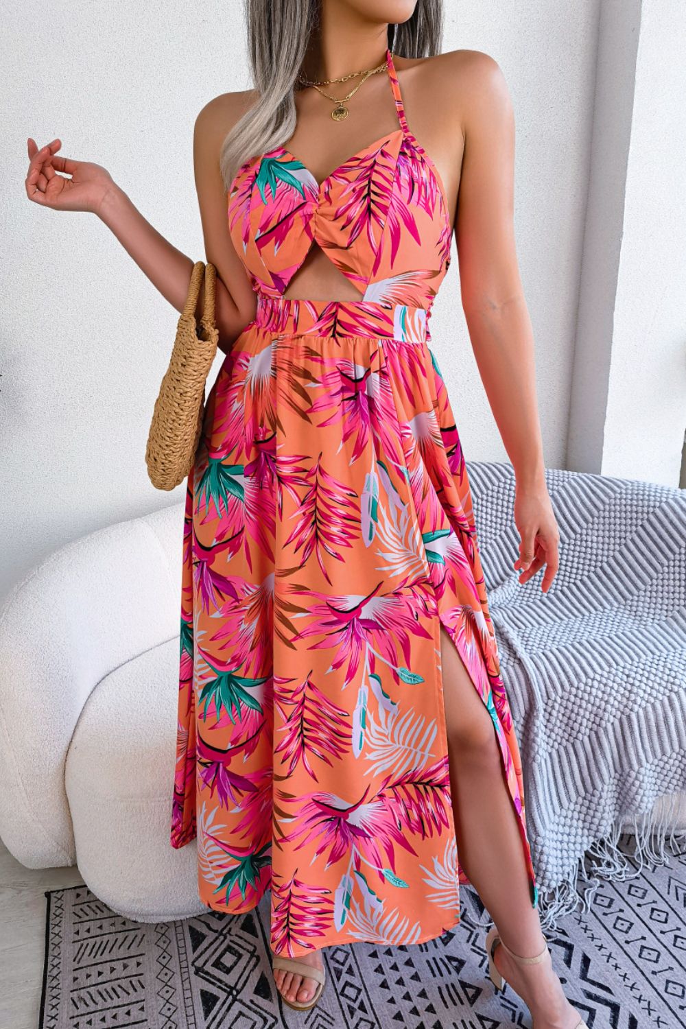 Tropical halter cutout maxi dress in orange with botanical print, featuring a knotted bust and thigh-high slit.
