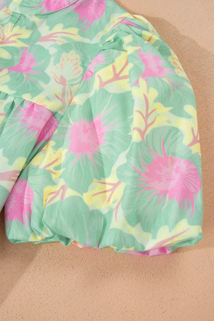 Pastel floral print polyester blouse with puff sleeves and ruffled hem detail.