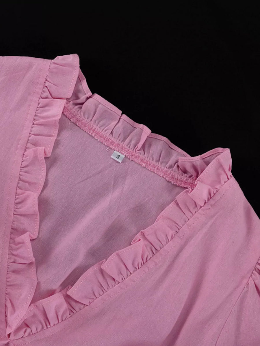 Pink ruffled v-neck blouse with a textured fabric and a size tag.