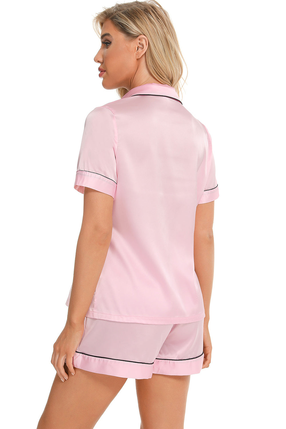 Pink satin pajama set with black piping detail, short sleeves and shorts.