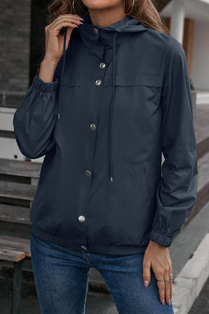 Dark blue hooded utility jacket with drawstring waist, snap buttons, and elastic cuffs.