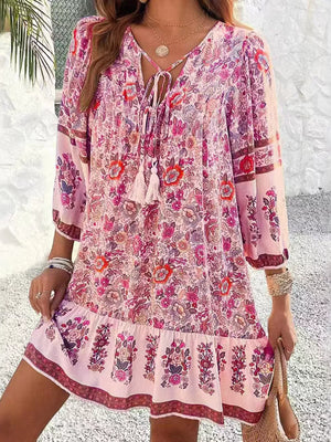 Vibrant floral print mini dress in blush pink with tassel tie neckline and tiered hem