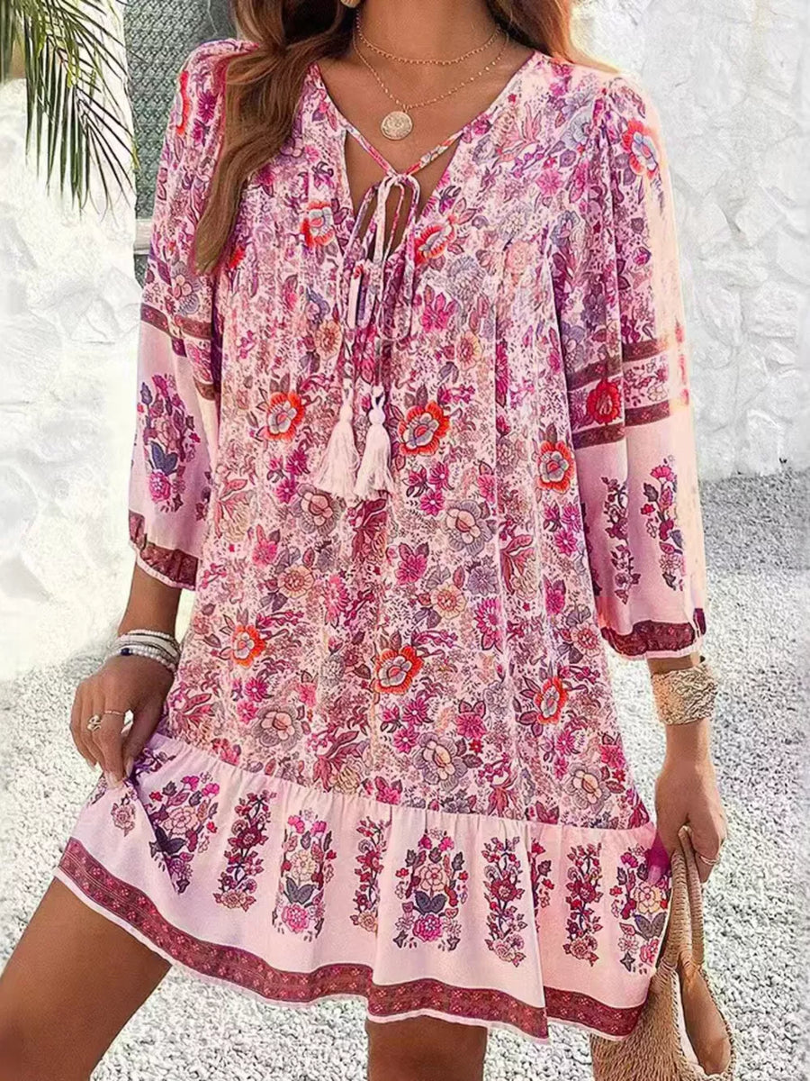 Vibrant floral print mini dress in blush pink with tassel tie neckline and tiered hem