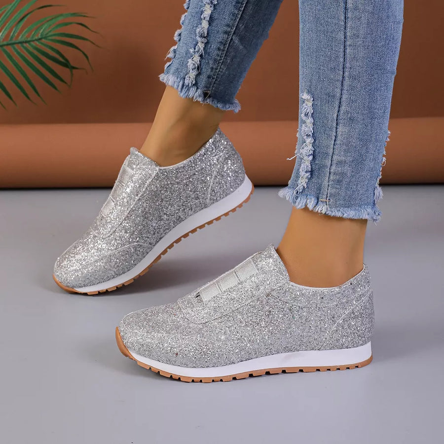 Silver glitter slip-on flats with elastic side panels and white soles.